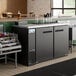 An Avantco black counter height back bar refrigerator with bottles on a shelf
