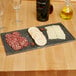 A group of sliced salami on a black GET Madison Avenue faux granite display board.