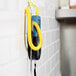 A Cooper-Atkins thermometer with a yellow DuraNeedle probe hanging from a wall.