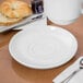 A white saucer with a white Libbey soup cup on it on a table.