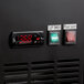 A close up of a digital clock and temperature control on a black Avantco back bar refrigerator.