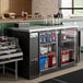 An Avantco back bar refrigerator with bottles of alcohol on shelves.
