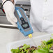 A hand holding a Cooper-Atkins EconoTemp thermocouple thermometer over a salad.