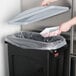 A black Rubbermaid Slim Jim trash can with a light gray handled lid on a counter.