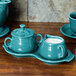 A turquoise Fiesta cream and sugar tray with cups and dishes on a white surface.