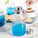 A Tablecraft glass mason jar filled with blue liquid and ice with a metal lid.