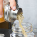 A person using a Tablecraft stainless steel Mason jar shaker cap to pour liquid into a jar.