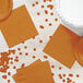 A table set with orange pumpkin spice luncheon napkins and plates.