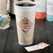 A close-up of a Dart Cafe G espresso foam cup on a counter with a lid and a packet of sugar.