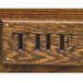 Dark oak wood with a carved letter 'e' on the surface.