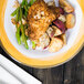 A Kanello melamine plate with chicken, potatoes, and green beans with a fork and knife.