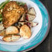 A Kanello melamine plate with chicken, potatoes, and green beans on a wood table.