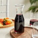 A Libbey glass wine decanter filled with red wine on a tray with food.