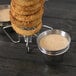 A Clipper Mill stainless steel Rocket Surfboard onion ring tower holding a stack of onion rings next to two ramekins of sauce.