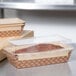 A brown rectangular loaf pan with a clear PET lid filled with baked goods.