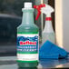 A bottle of Noble Chemical Reflect Super Concentrated Window Cleaner next to a spray bottle.