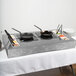 A Tablecraft countertop induction station with two pans and spoons on a table.