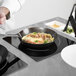 A person using a Tablecraft aluminum double countertop induction station to cook food in a pan.