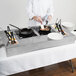 A chef preparing food on a Tablecraft Random Swirl Aluminum Double Countertop Induction Station.