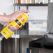 A person holding a yellow PAM spray can over a grill.