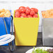 A yellow Tablecraft salad crock on a table with tomatoes.