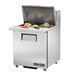 A True stainless steel commercial sandwich prep table with food on top.