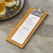 A Choice natural wood menu holder with a menu on a wood board.