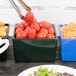 A Tablecraft hunter green bowl filled with tomatoes on a table of food.