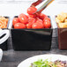 A Tablecraft midnight speckle bowl filled with tomatoes on a table.