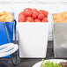 A white Tablecraft rectangular bowl on a table filled with tomatoes.