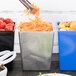 A person is grating carrots into a Tablecraft metal bowl.