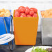 A Tablecraft orange bowl full of tomatoes on a table in a salad bar.