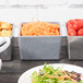 A Tablecraft granite bowl filled with shredded cheese on a table with bowls of food.