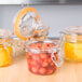 A group of Tablecraft glass condiment jars filled with food on a table.