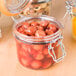 A Tablecraft glass condiment jar filled with olives on a table.