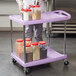 A purple Metro utility cart with two shelves holding plastic containers and a bag of spices.