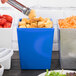 A person using a fork to put croutons into a blue Tablecraft straight sided bowl.