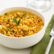 A white bowl of dried yellow split peas with parsley on top.