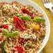 Dried whole pearl barley in a bowl of farro salad with roasted red peppers and basil.