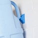 A blue plastic container hanging on the wall with a blue handle.