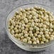 A bowl of dried whole green peas on a table.