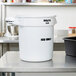 A white Rubbermaid ProServe "ICE ONLY" bucket on a table.