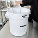 A woman using a Rubbermaid white "ICE ONLY" bucket to hold a glass of ice.