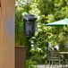 A Lavex Zap N Trap bug zapper hanging from a green umbrella over a table on an outdoor patio.