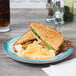 A Kanello melamine plate with a sandwich and chips on it on a table.