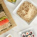 A wooden table with white bowls of sushi rice and vegetables and a plate of Regal brown rice and sushi.