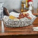 A Clipper Mill stainless steel oval grid basket of food on a table.