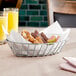 A Clipper Mill chrome oval grid basket filled with food on a table.