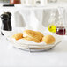 A Clipper Mill stainless steel oval basket with rolls on a table.