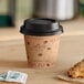 A Choice Cafe print paper hot cup with a black lid and a pastry on a table.